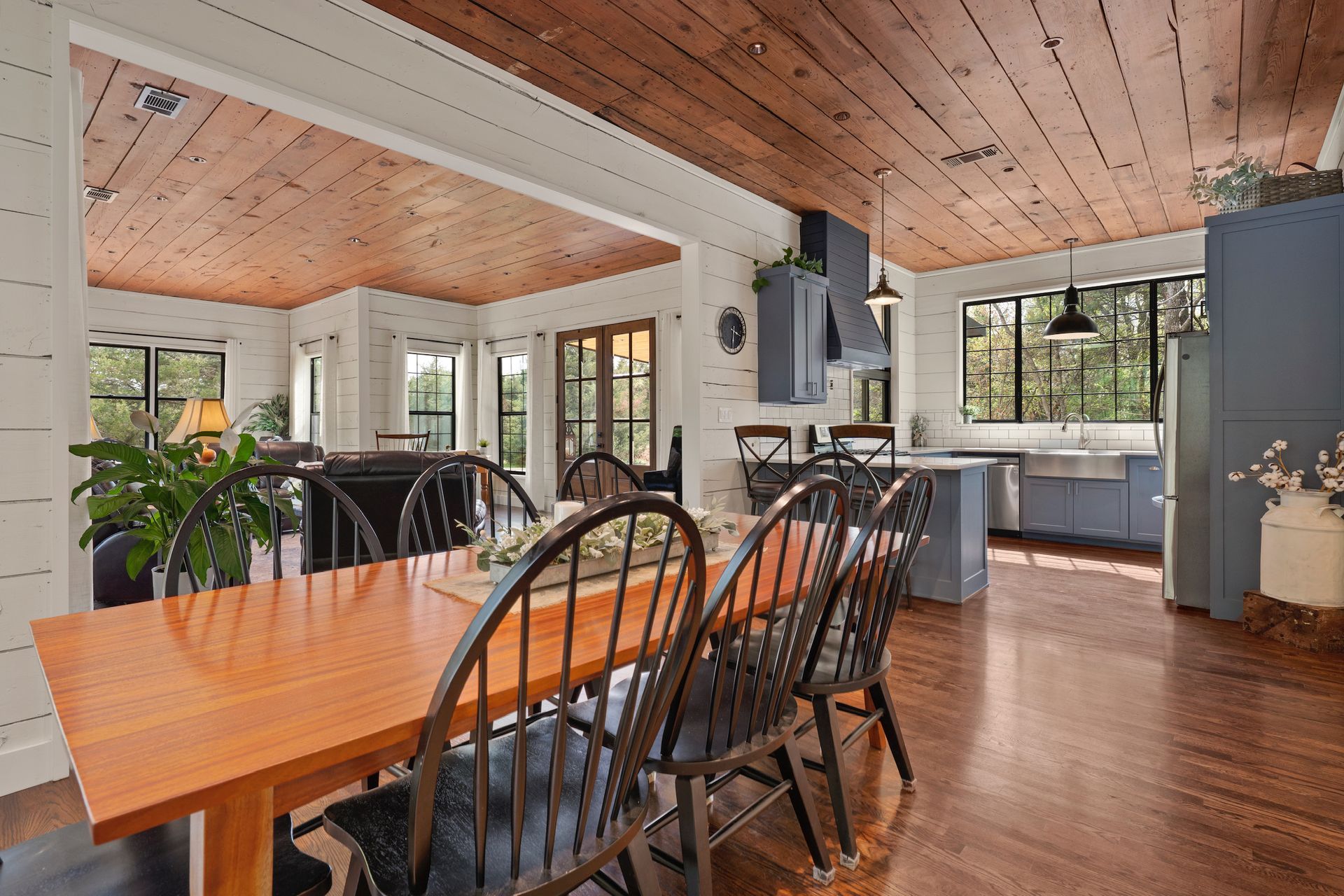 Dining room with wood table, black chairs, wood ceiling, and blue cabinets.
