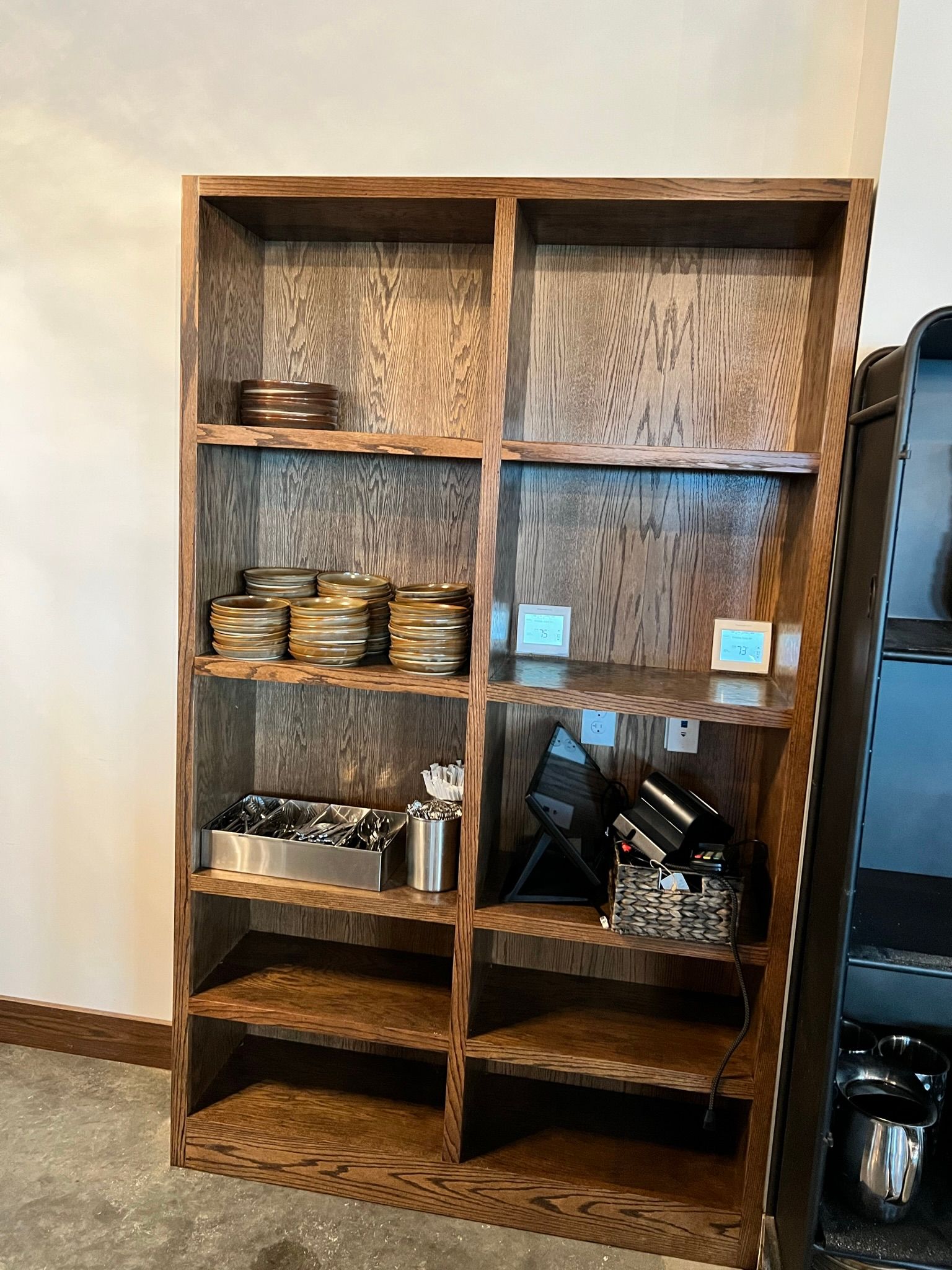 Wooden shelf filled with various metal containers and objects against a wall.