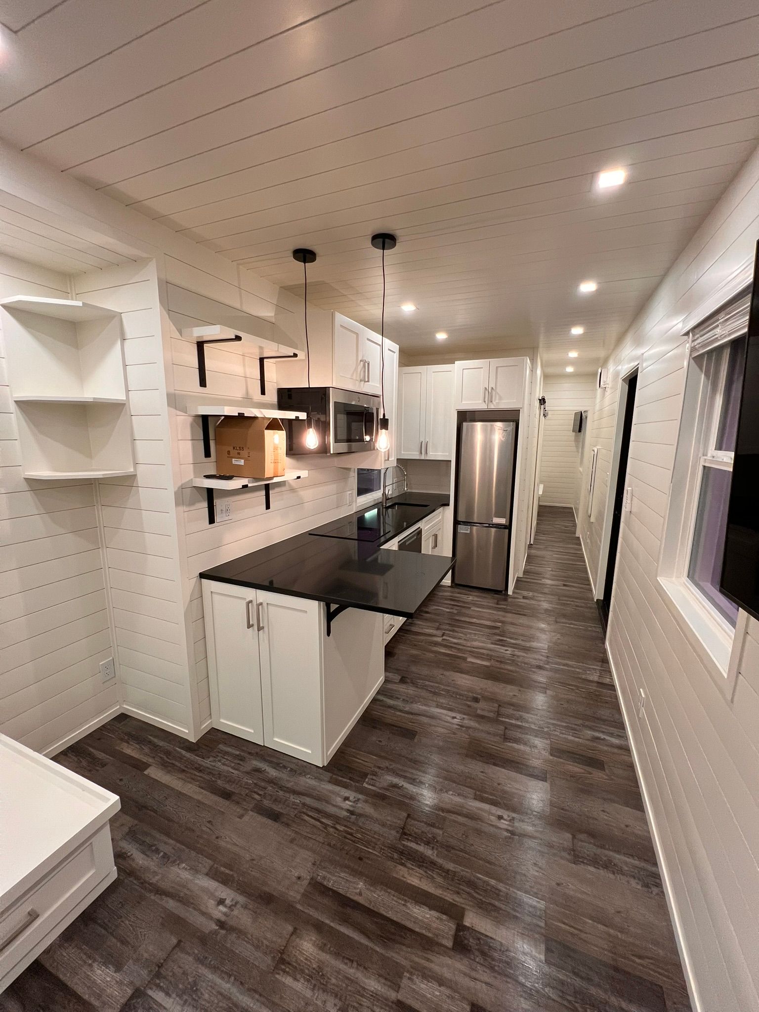 Modern kitchen with white cabinets, dark countertops, and stainless steel appliances.