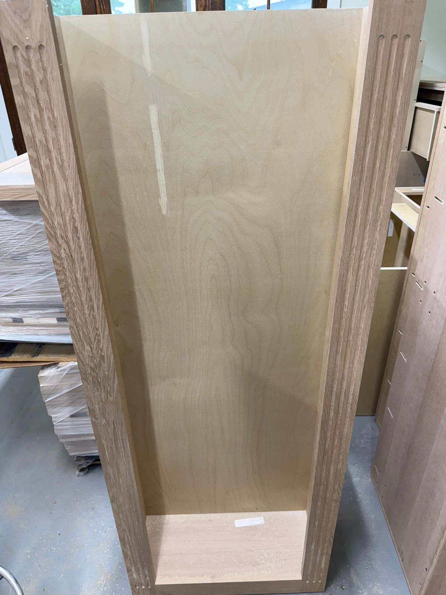 Open cabinet frame made of light wood with decorative trim.