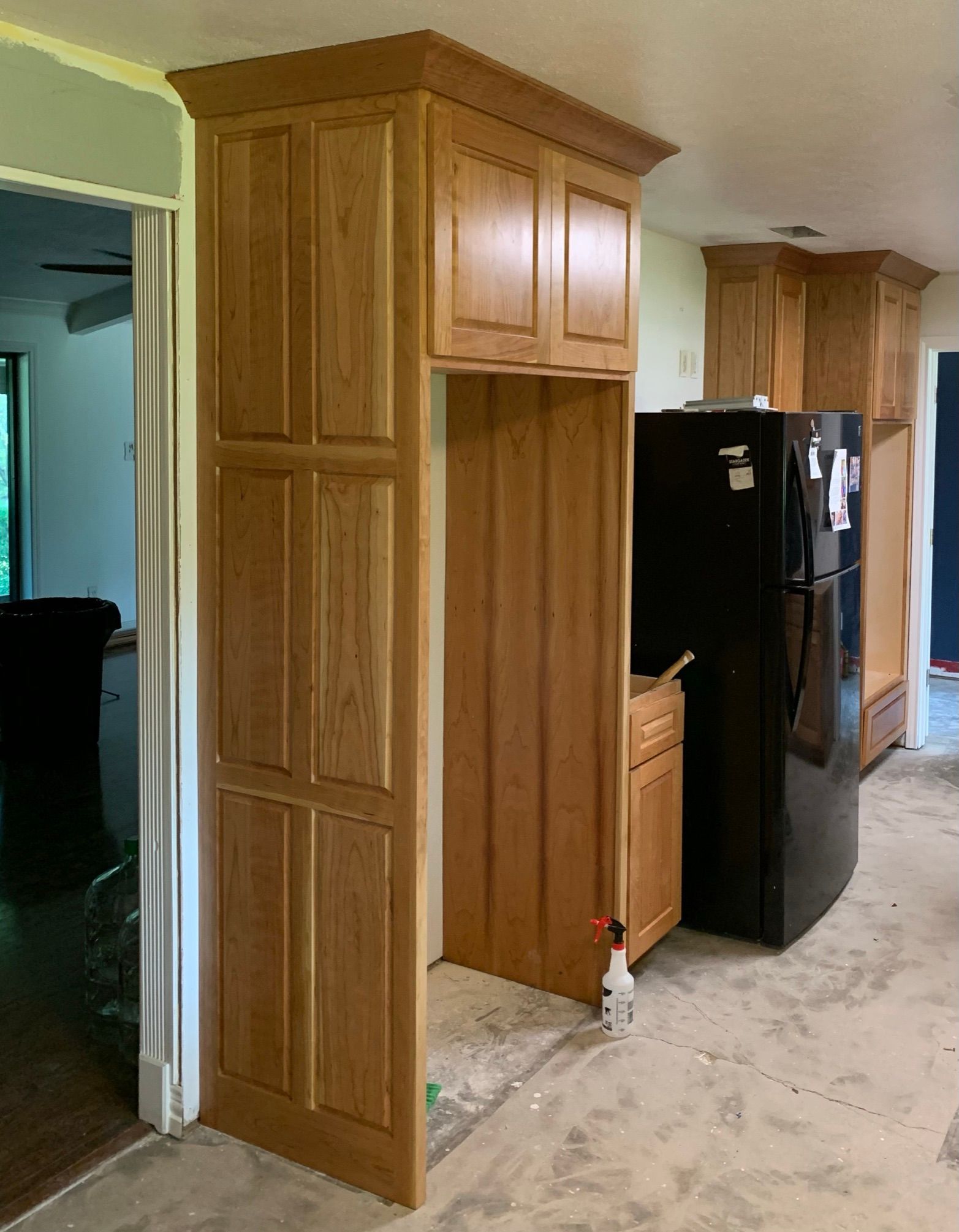 Wooden kitchen cabinets surround a refrigerator space; new kitchen remodel.