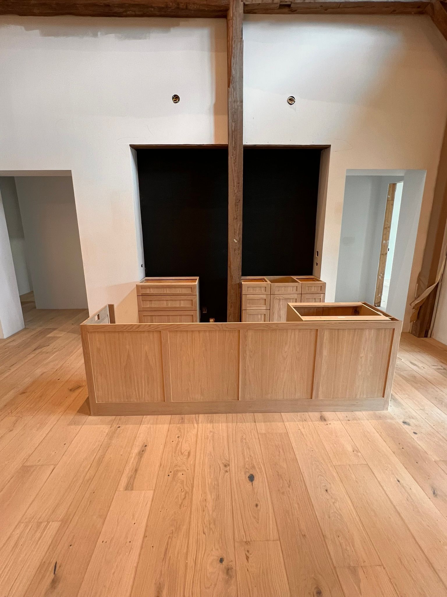 Wooden kitchen island with cabinets in a room with hardwood floors and black wall.