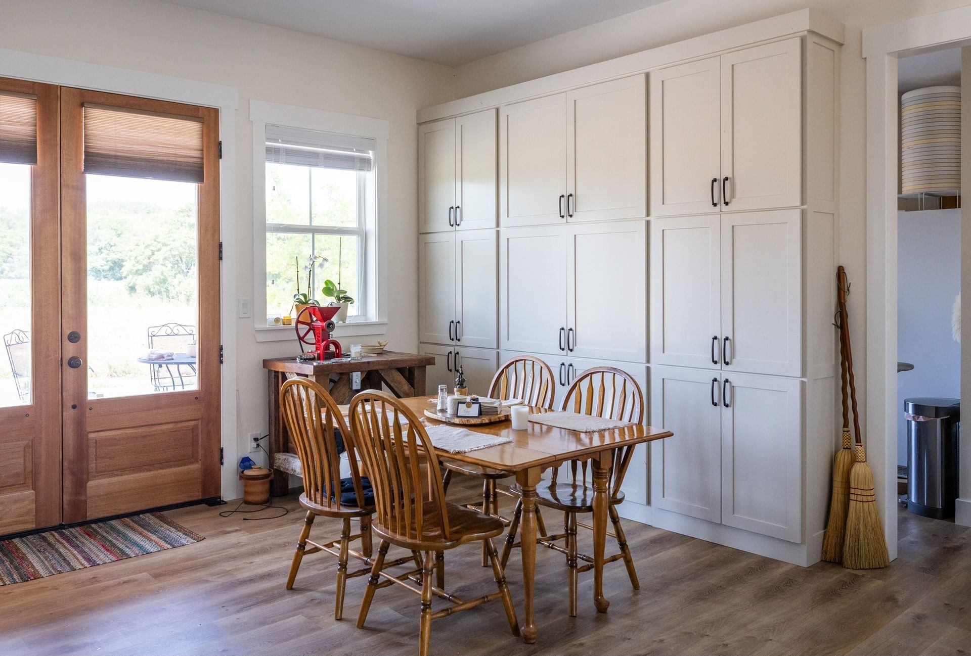 Dining room with wooden table and chairs, white cabinets, and a doorway.
