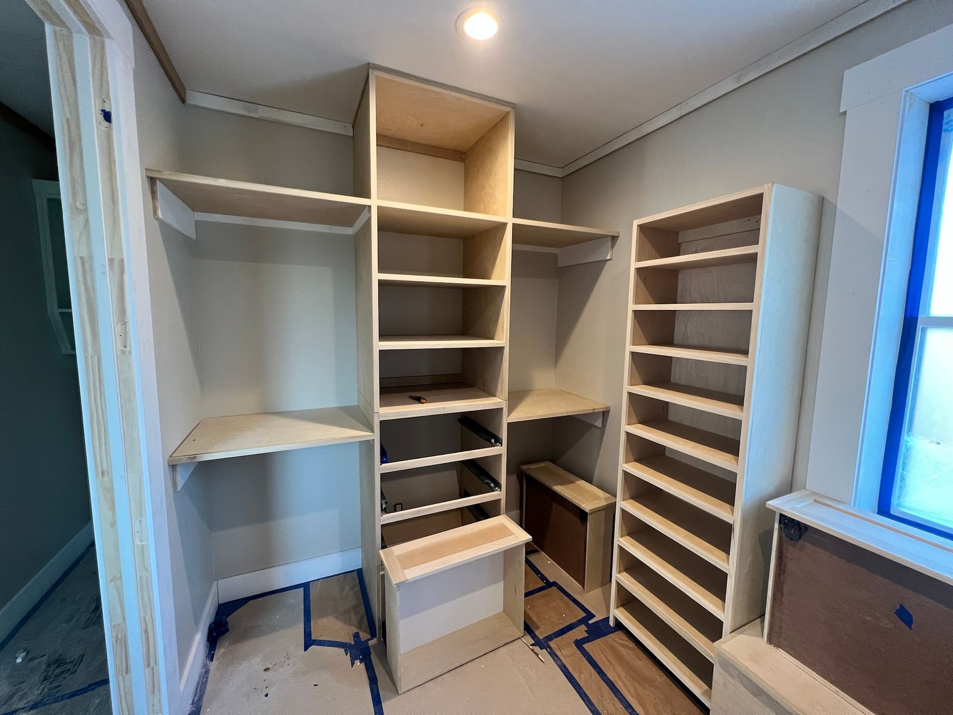 Unfinished closet with built-in shelving and hanging rods. Light-colored wood and neutral walls. 