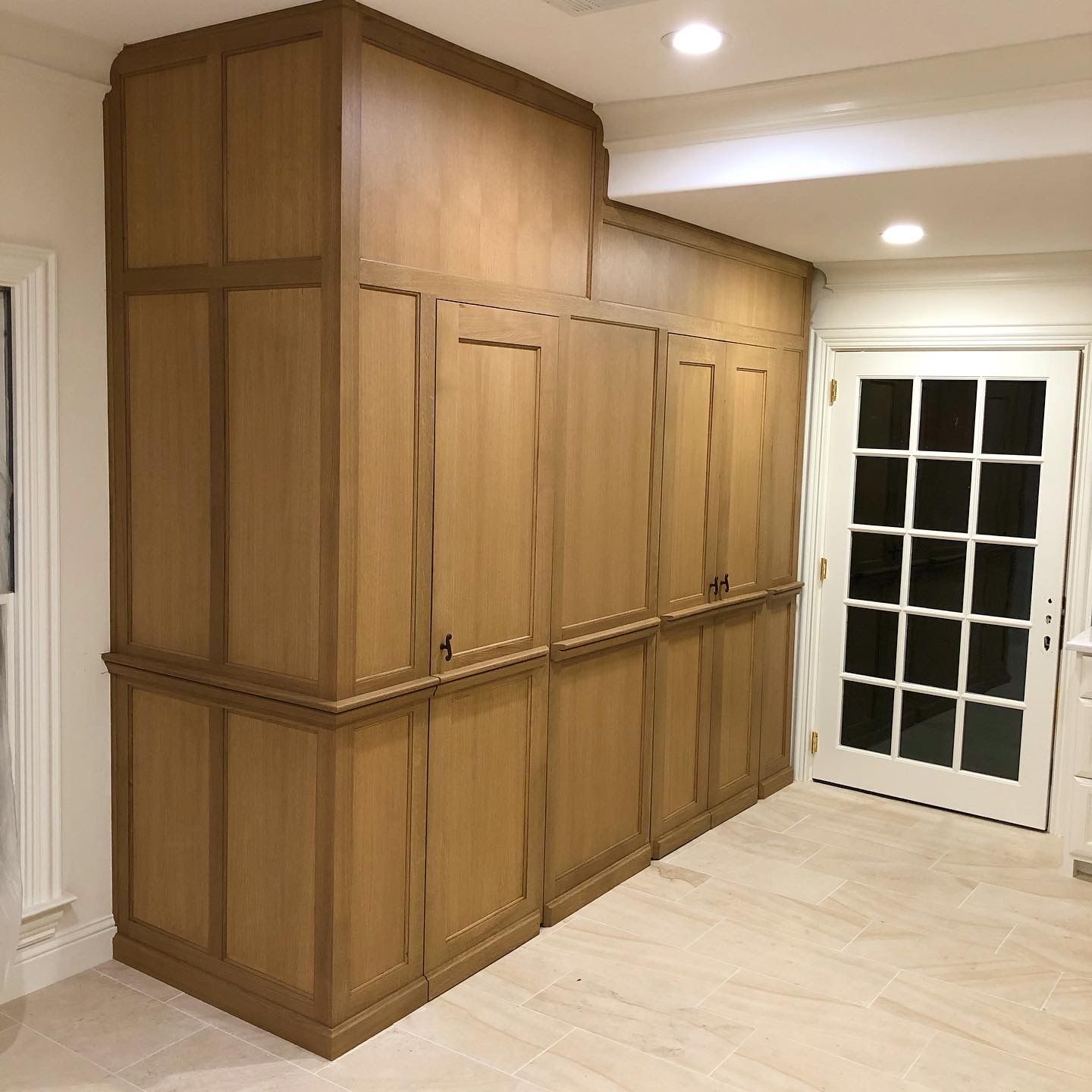 Wooden cabinets against a wall, with a door and window to the side.