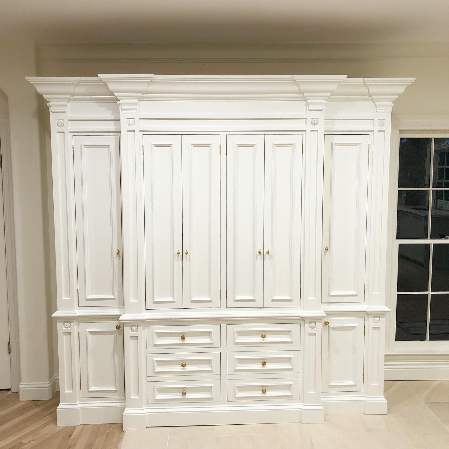 White painted wooden cabinet with doors, drawers, and decorative molding.