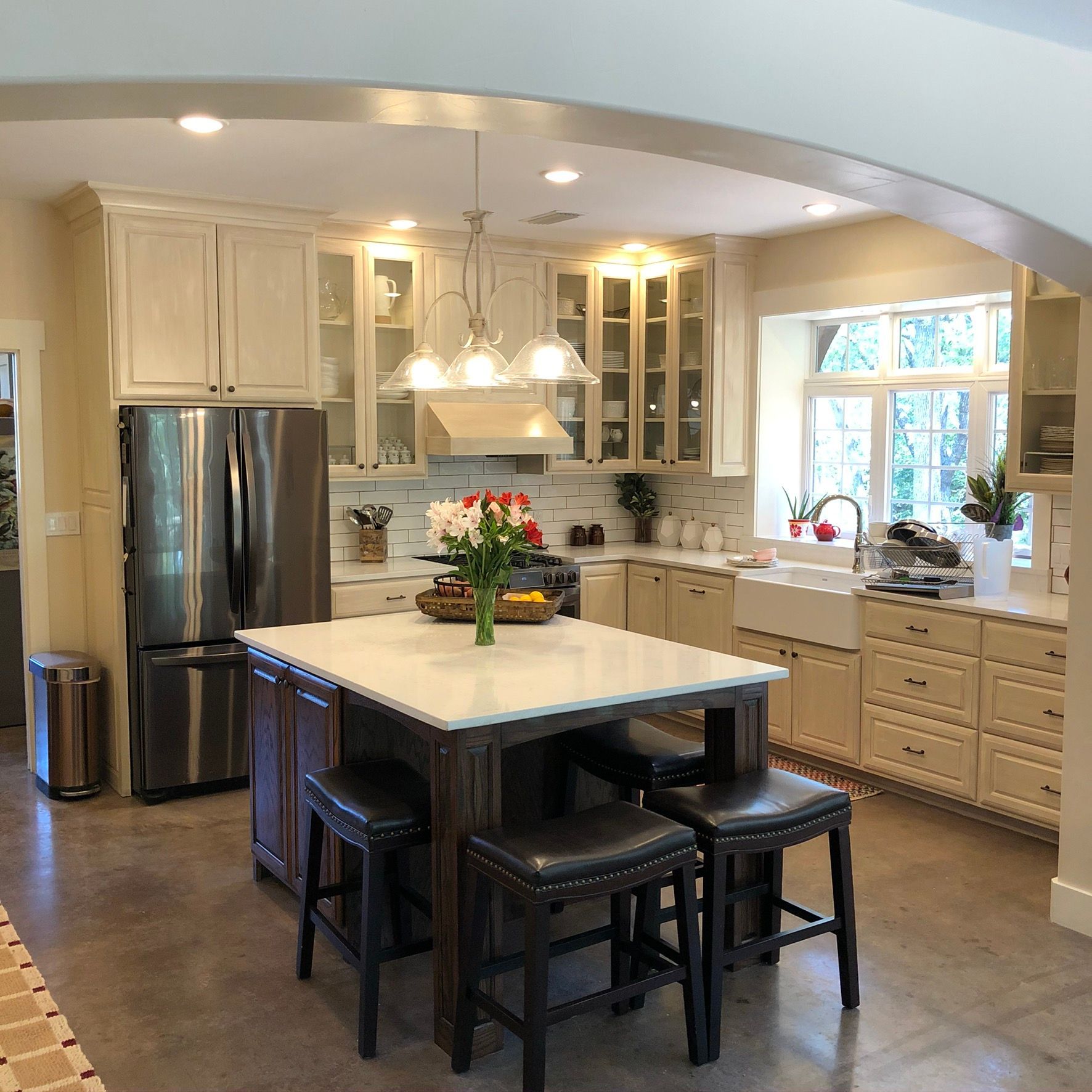 Kitchen with cream cabinets, stainless steel appliances, and an island with stools.