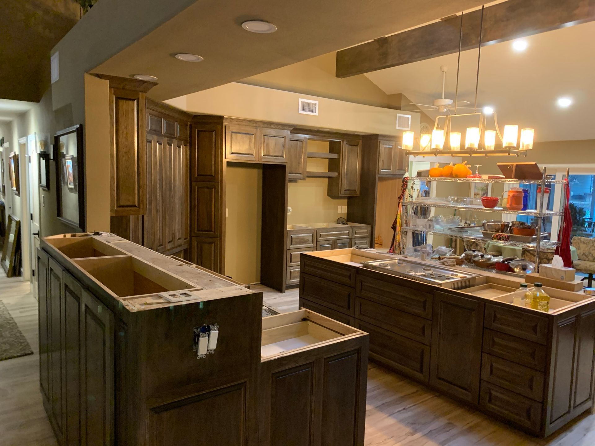 Kitchen under construction with dark brown cabinets, island, and overhead lighting.