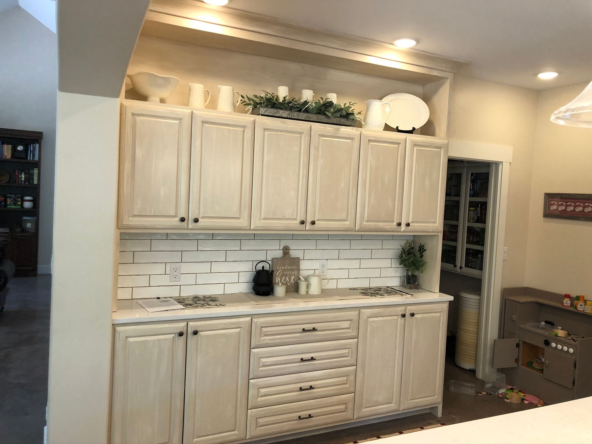 White kitchen cabinets with decor, and a pantry door.