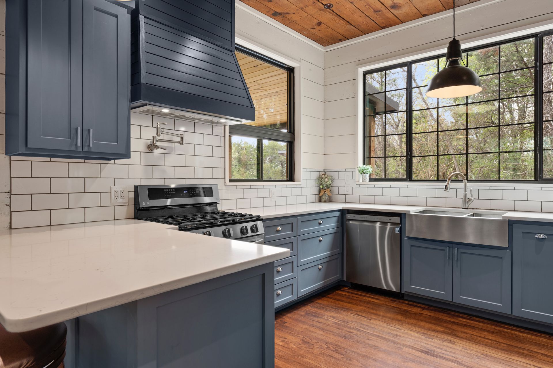 Modern kitchen with blue cabinets, stainless steel appliances, and white countertops.