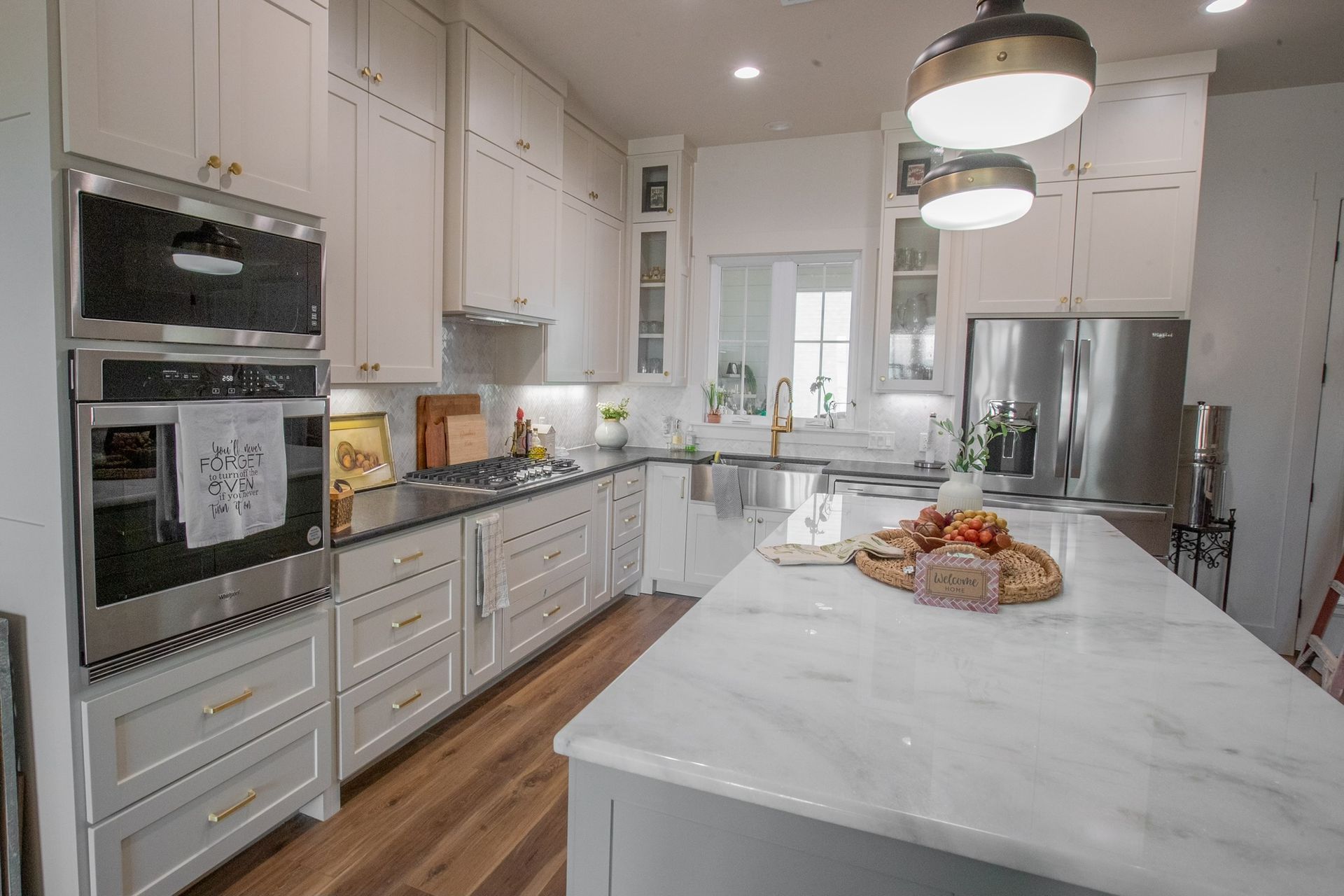 Modern kitchen with white cabinets, stainless steel appliances, and a marble island.