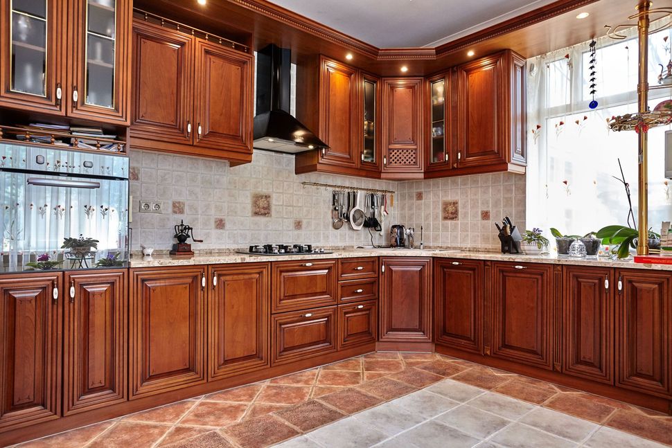 Wooden kitchen with cabinets, stove, and tile backsplash.