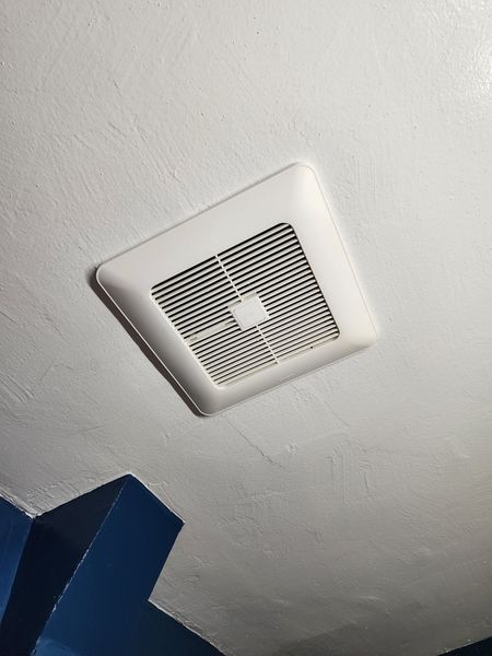 White square bathroom exhaust fan on a white ceiling.