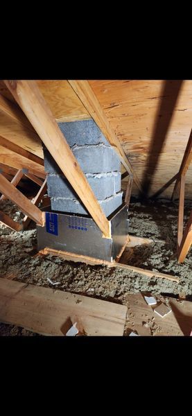 An attic interior with a ductwork system enclosed in metal and layered boxes.