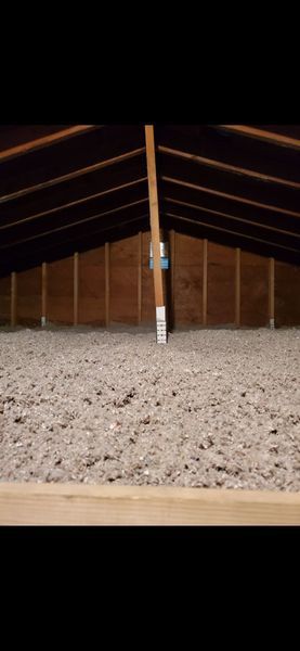 Attic filled with insulation; wooden rafters and supports are visible above the insulation.