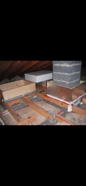 View of an attic with wood framing, a chimney, and various structures.