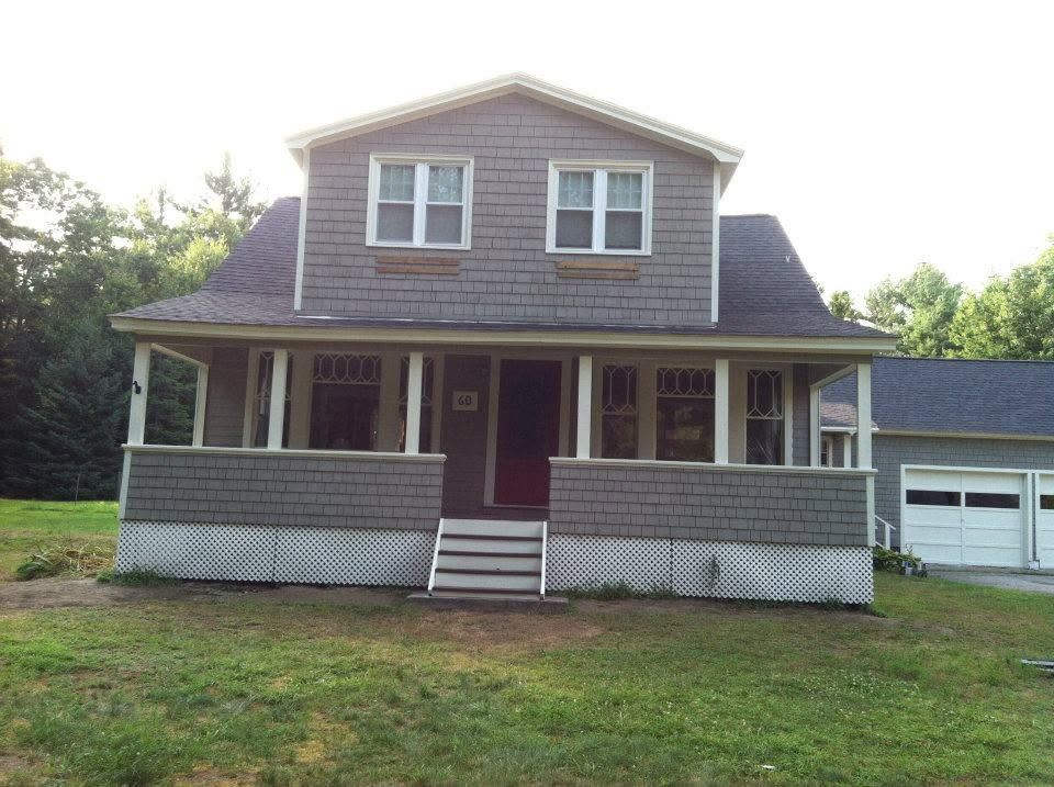Two-story gray house with red front door, white porch railing, and a garage on the right.