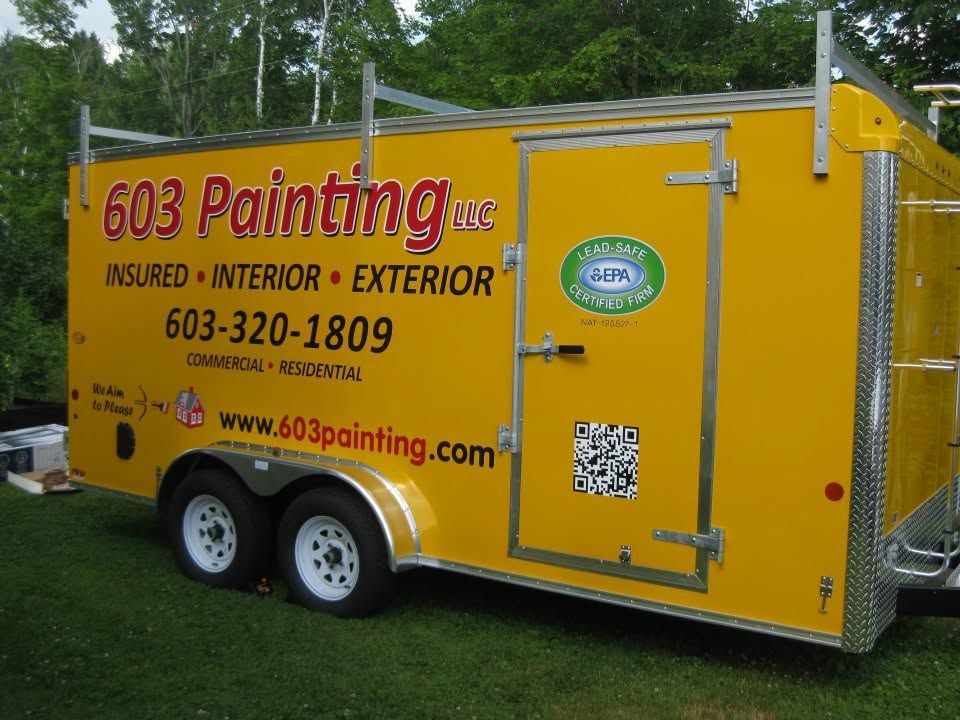 Yellow 603 Painting trailer with company logo and contact info parked on grass.