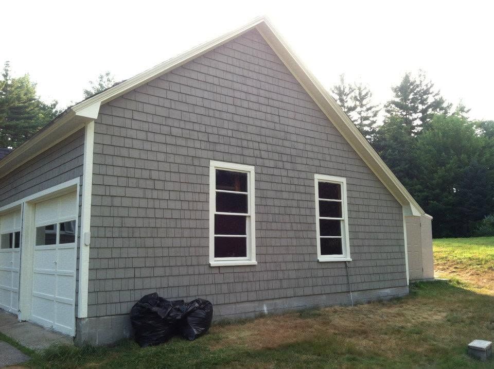 Gray house exterior with gabled roof, white trim, and two narrow windows beside a garage.