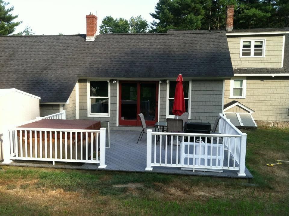 Back deck with white railings, gray house, and red patio umbrella under a covered porch.