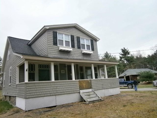 Gray two-story house with front porch, steps, and white trim on a residential street