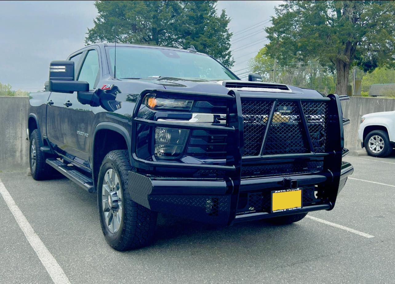 A black truck with a grille is parked in a parking lot.