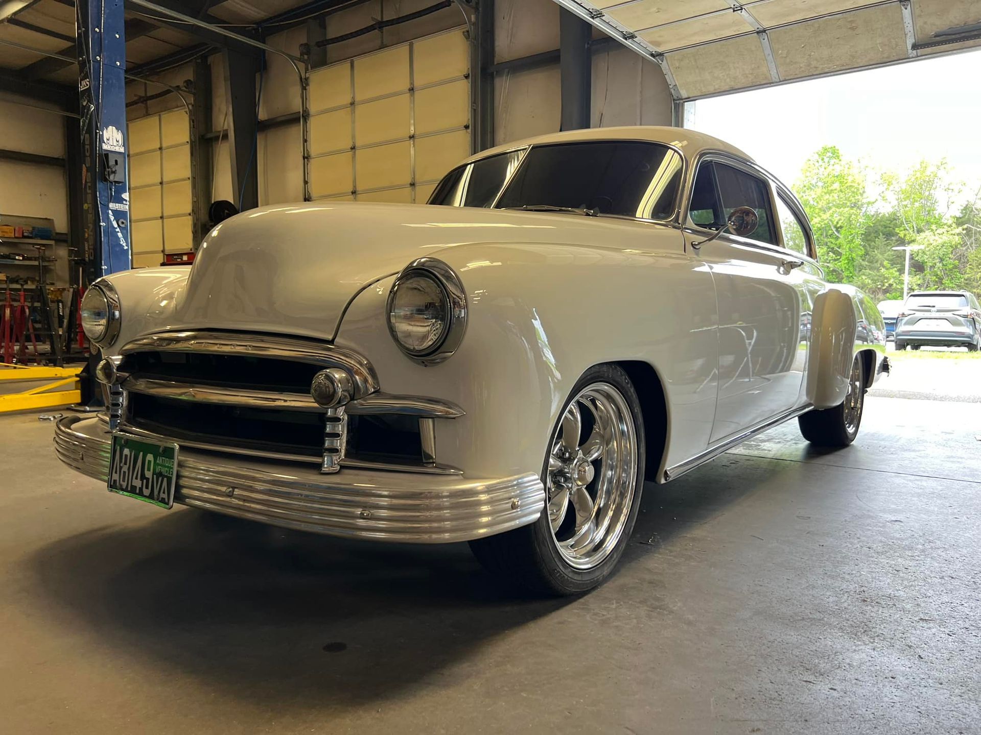 A white car is parked in a garage next to a garage door.