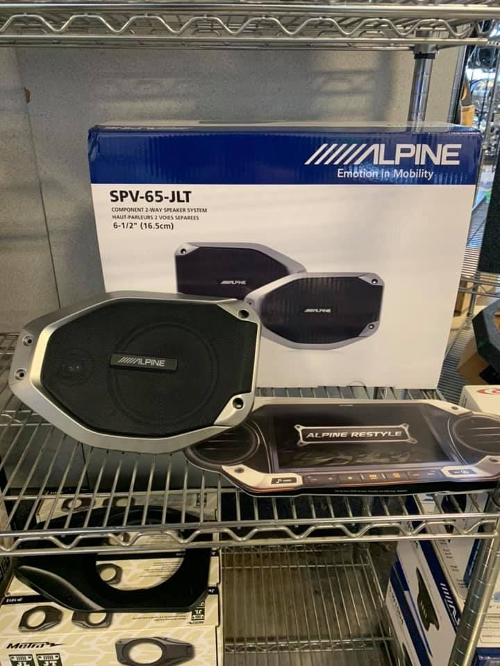 A pair of alpine speakers sitting on top of a shelf next to a box.