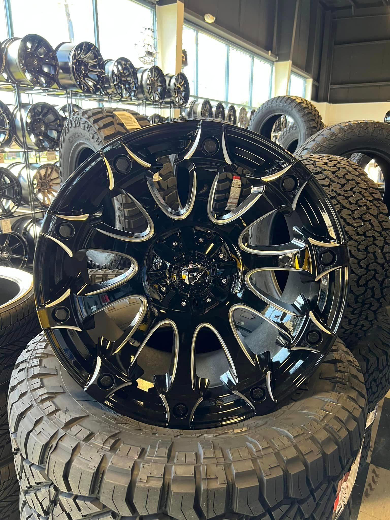 A black wheel is sitting on top of a pile of tires.