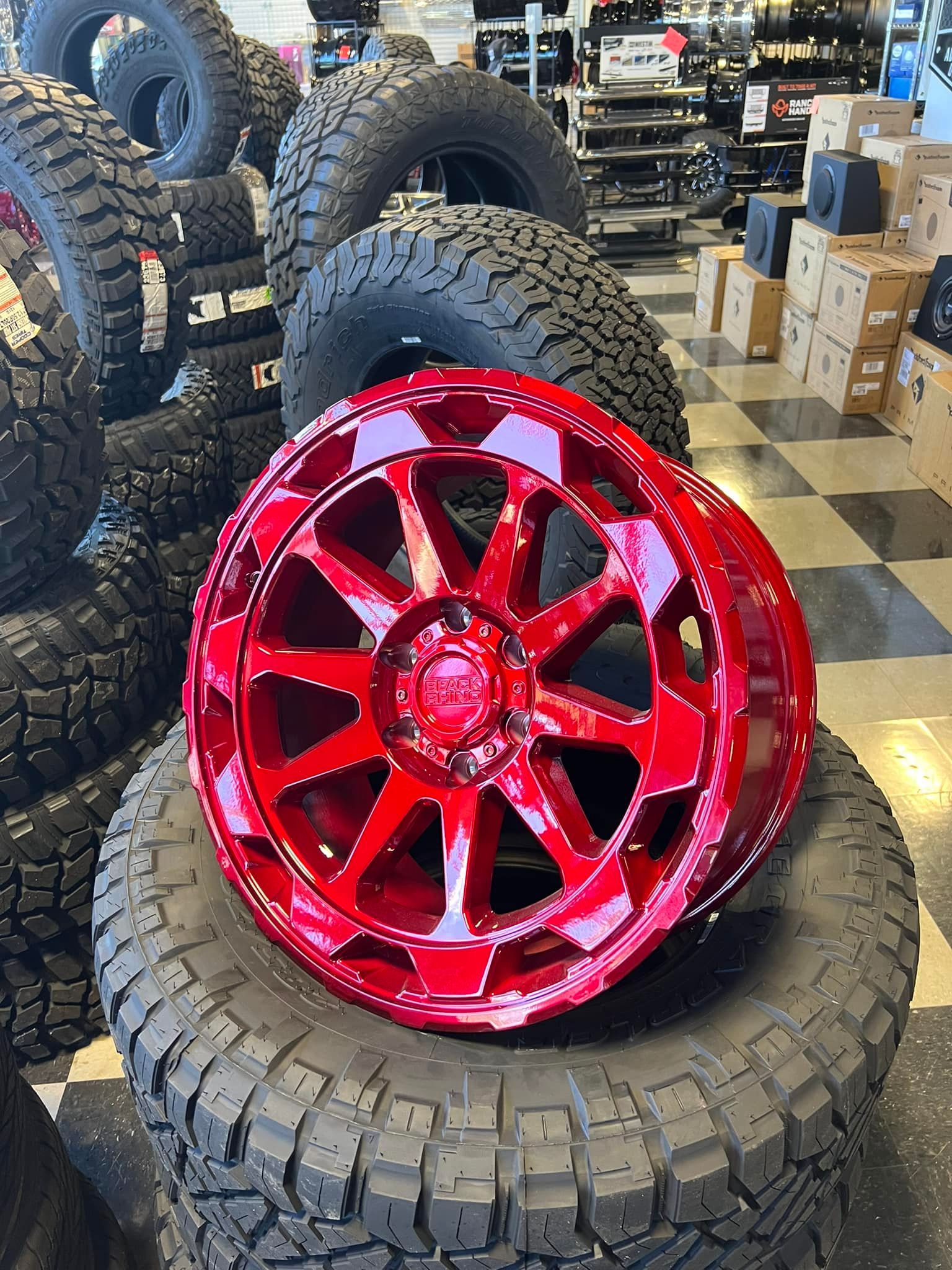 A red wheel is sitting on top of a tire in a store.