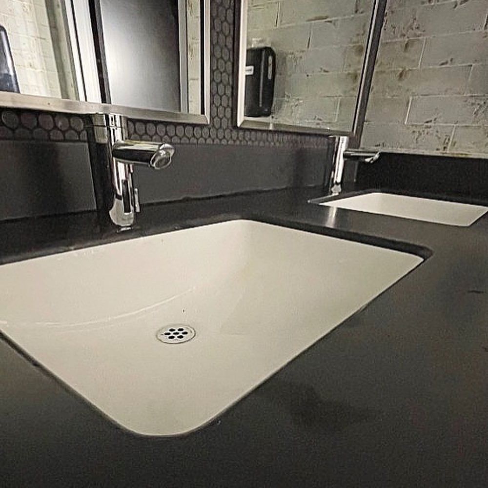 A bathroom sink with two faucets and a mirror