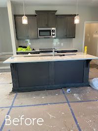 A kitchen with a large island in the middle is being remodeled.