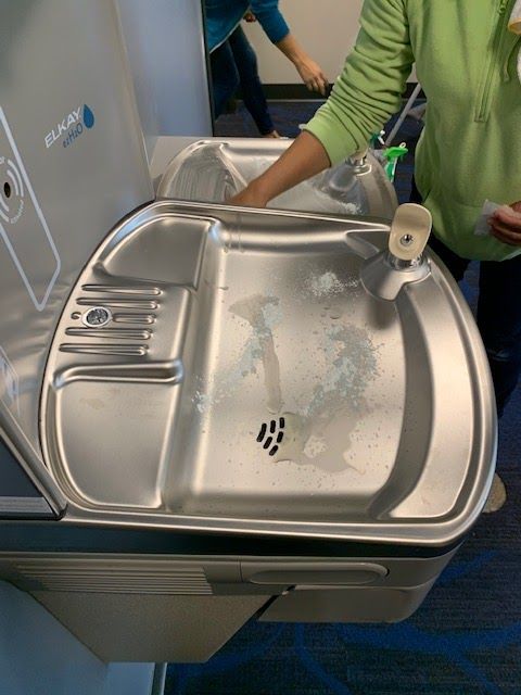 A person is cleaning a stainless steel water fountain