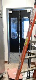 A ladder is sitting in front of a door in a kitchen.