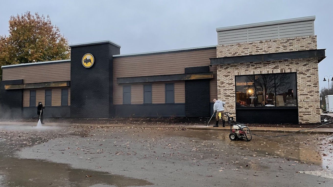 A man is cleaning the outside of a building with a pressure washer.