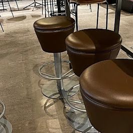 A row of brown bar stools are sitting next to each other in a room.