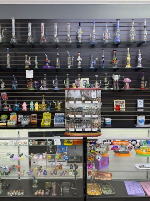 A smoke shop interior featuring multiple glass water pipes on display shelves and in glass display cases.