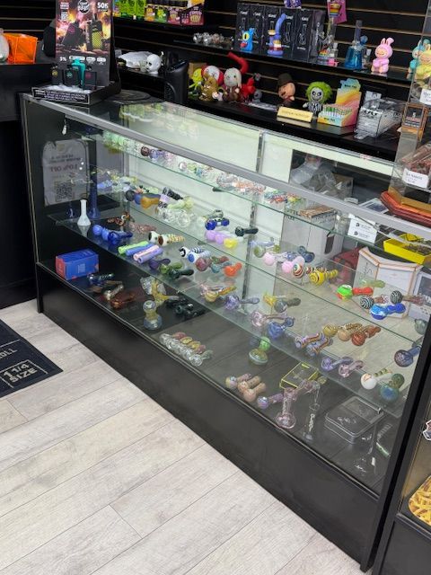 A glass display case in a store stocked with colorful glass pipes and smoking accessories.