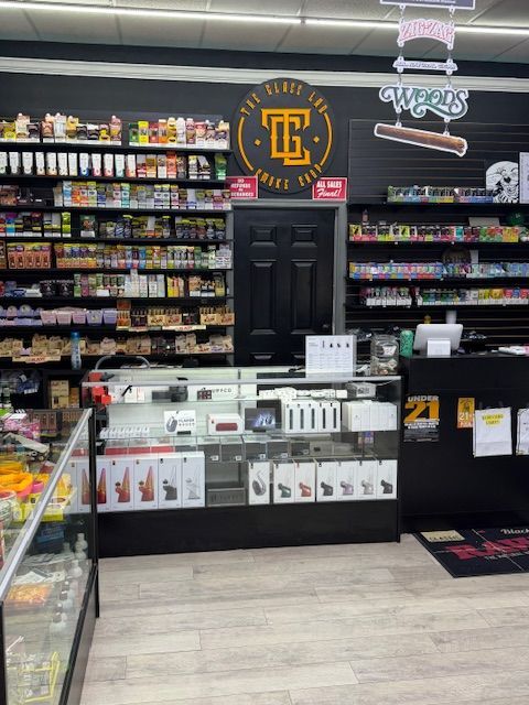 Interior of a vape shop with shelves of products and a central display case. THE THIRD EYE logo visible.