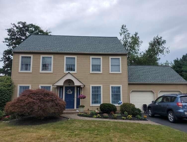 Two-story beige house with blue trim, attached garage, and a parked SUV in the driveway