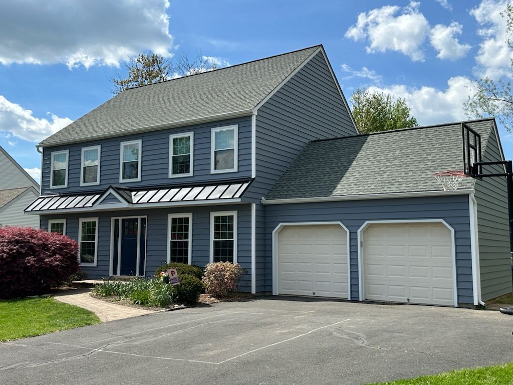 Suburban two-story gray house with attached double garage and driveway under a blue sky
