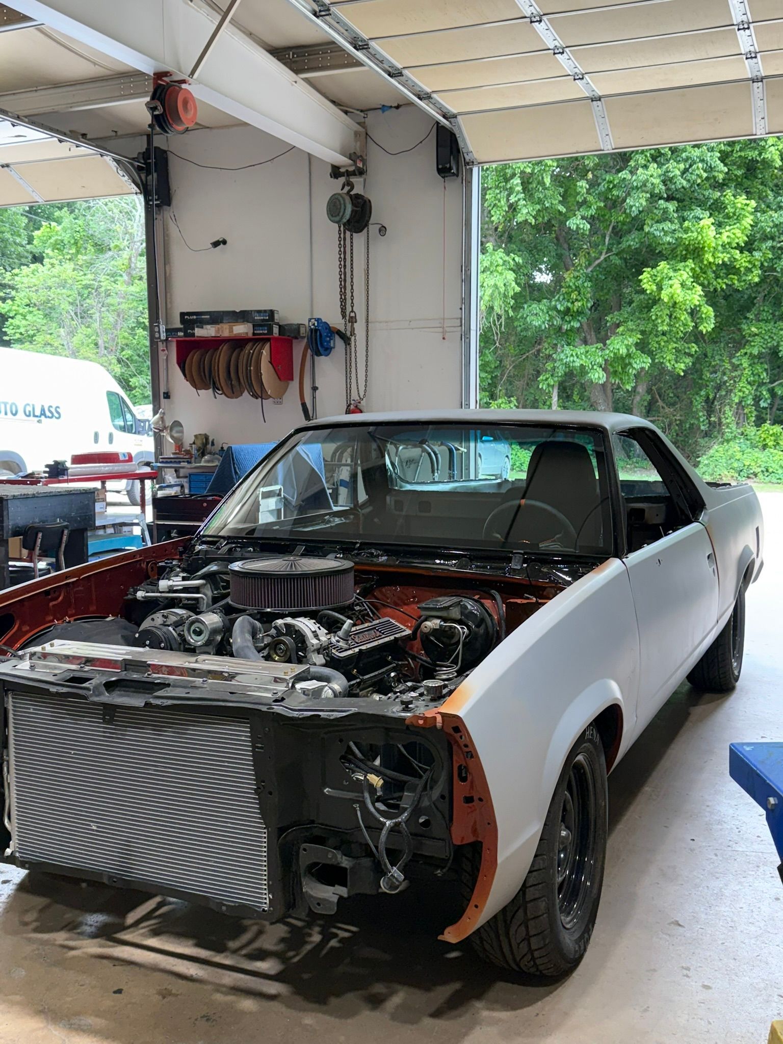 Black classic car under repair in a garage, front end removed and engine exposed