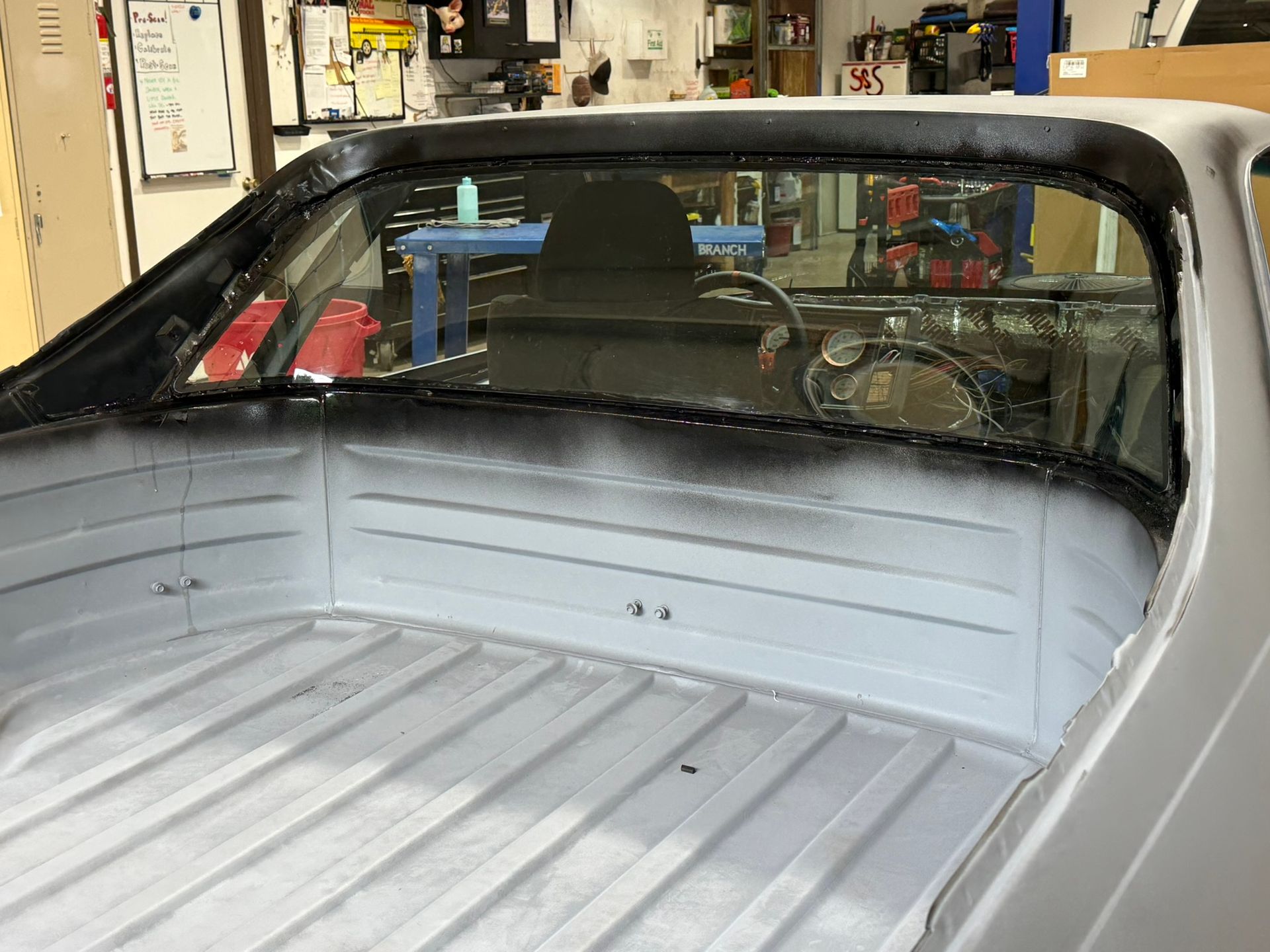 White vintage car interior with an empty open bed in a garage, viewed from the rear