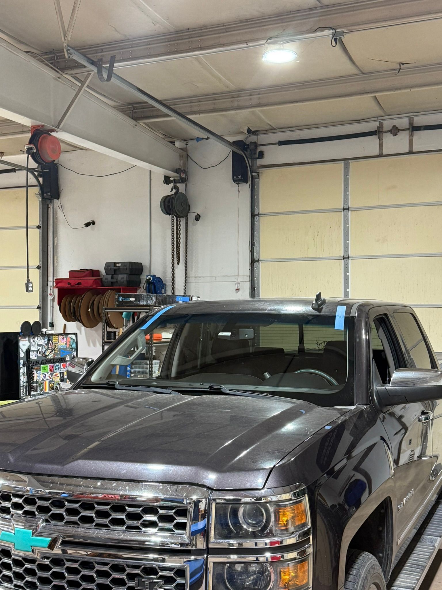 Gray pickup truck in a garage overhead lifts and tools in the background.