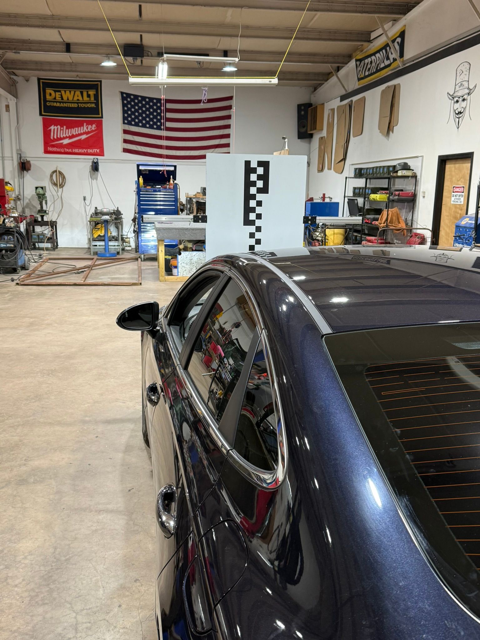 Black race car in a workshop garage with an American flag on the back wall