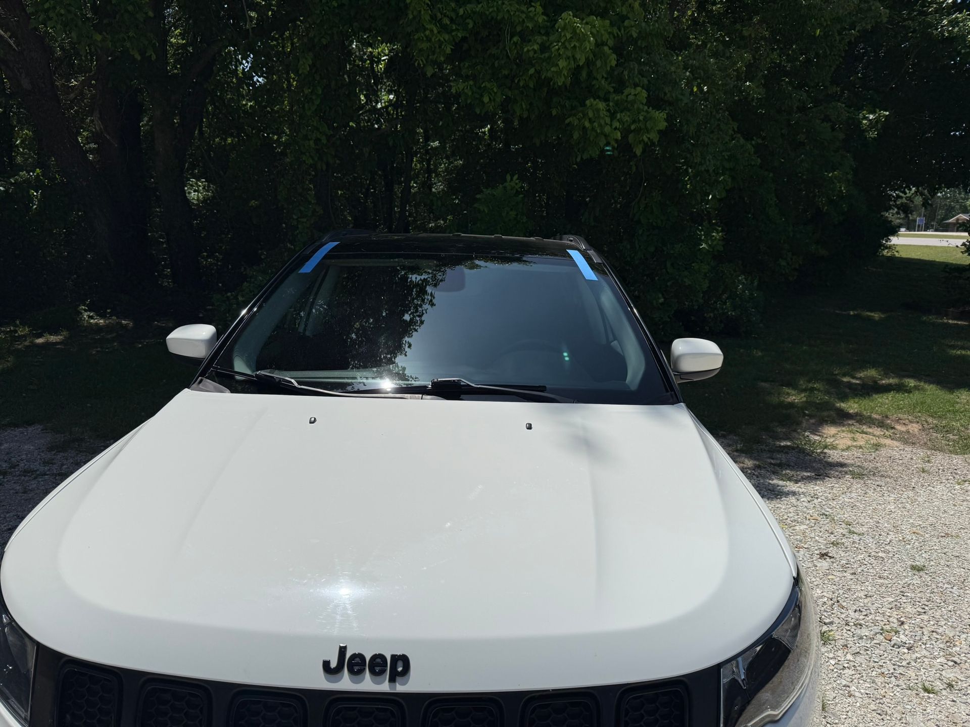 White Jeep SUV parked under trees in a shaded outdoor area