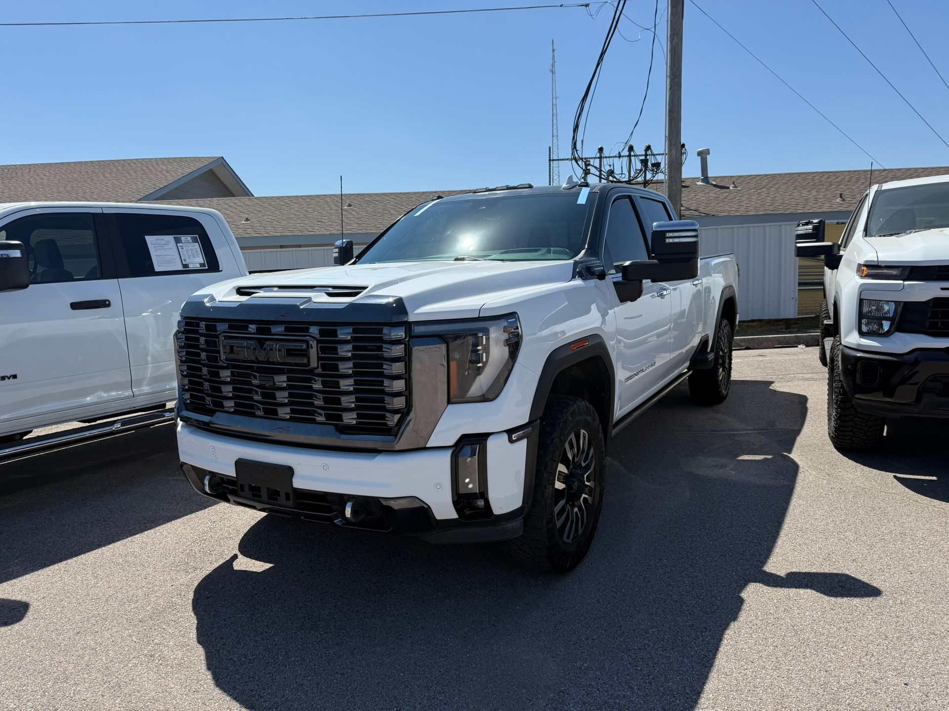 White and black pickup truck parked outdoors in a dealership lot on a sunny day