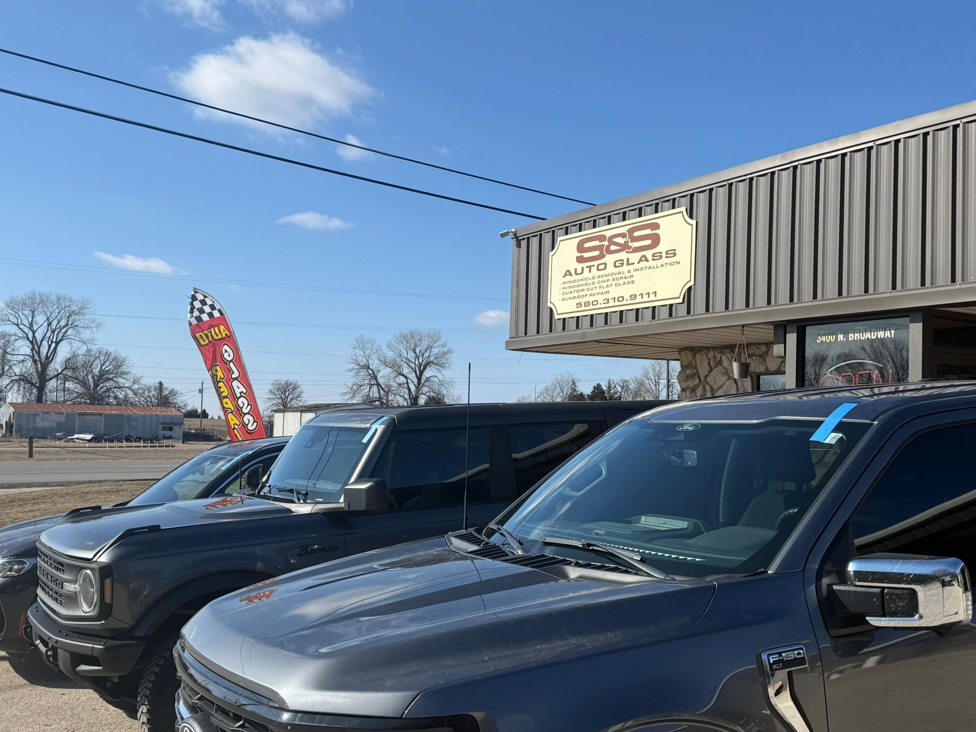 Vehicles parked outside a business called S & S Auto Repair. Sunny day.
