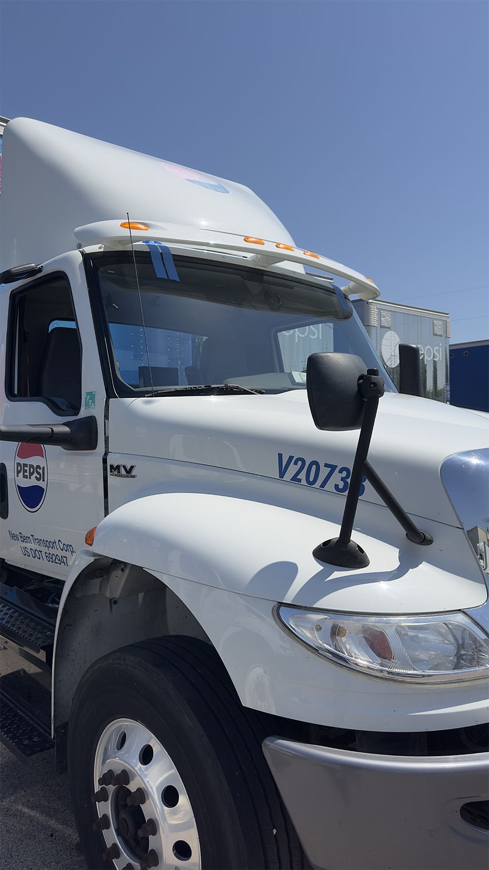 White semi-truck cab with raised hood against a clear blue sky.