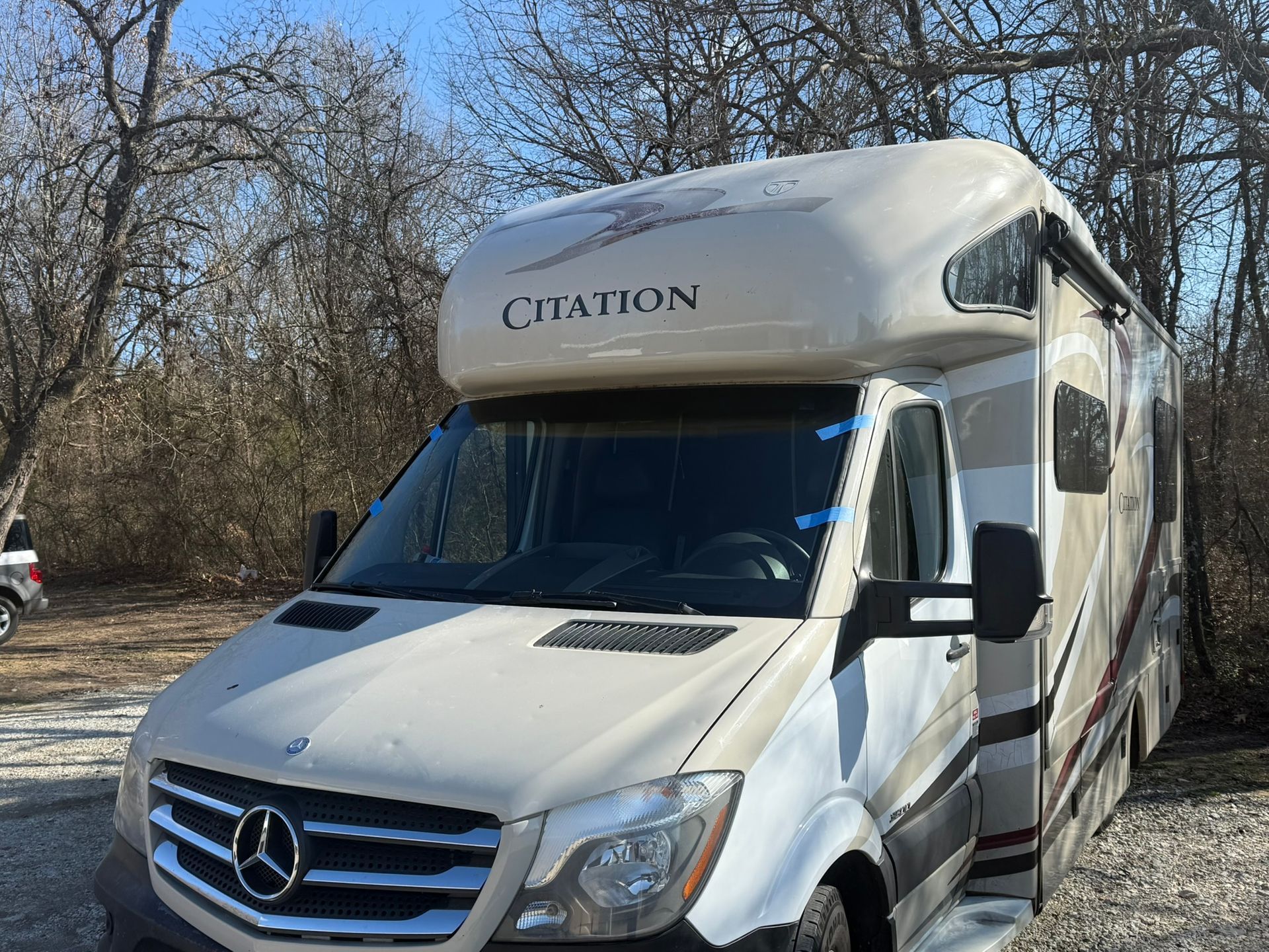 Tan and white RV parked outdoors on a sunny day; the RV has Creation on its front.